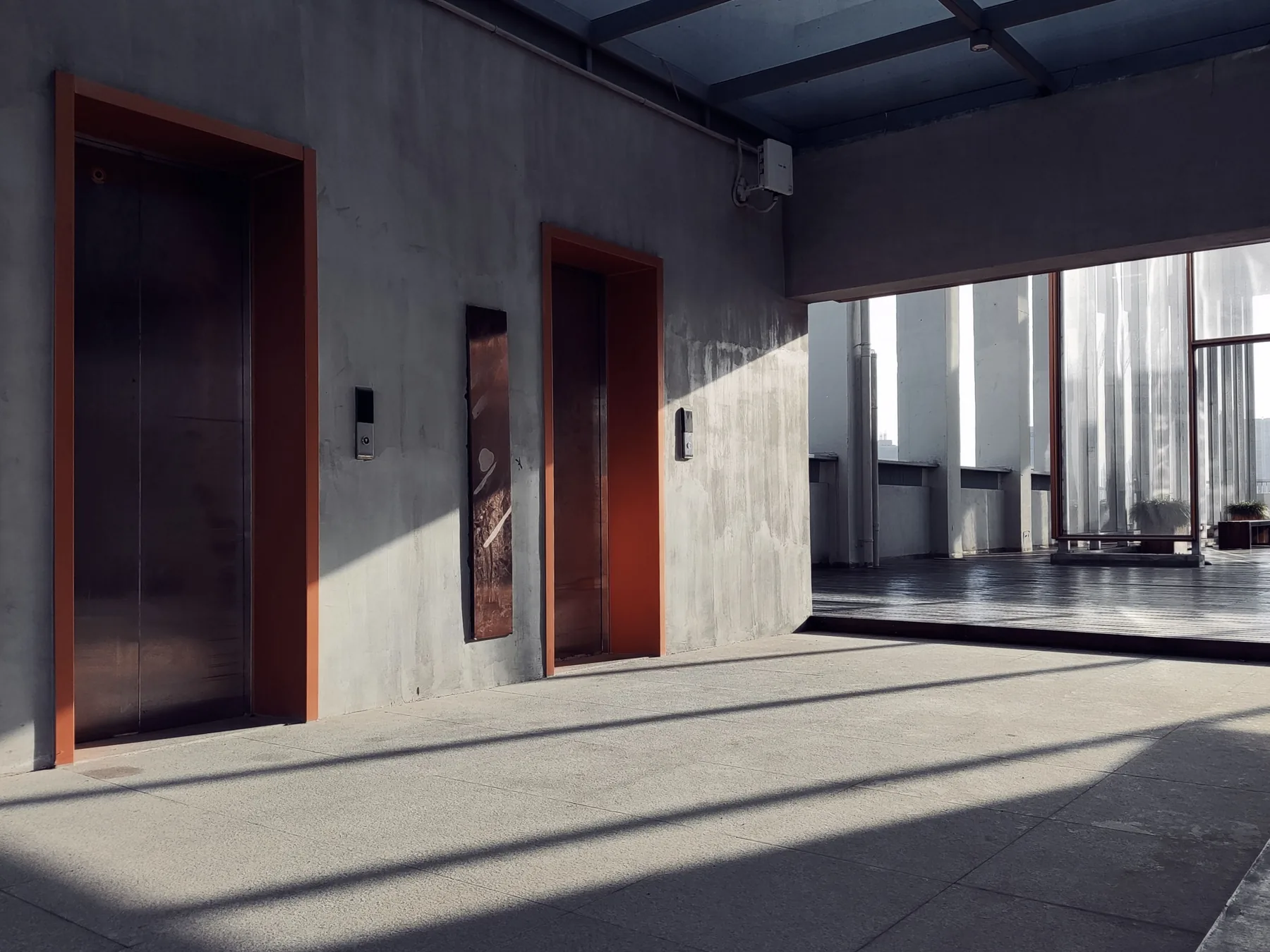 Two elevator doors opening from a clear concrete lobby